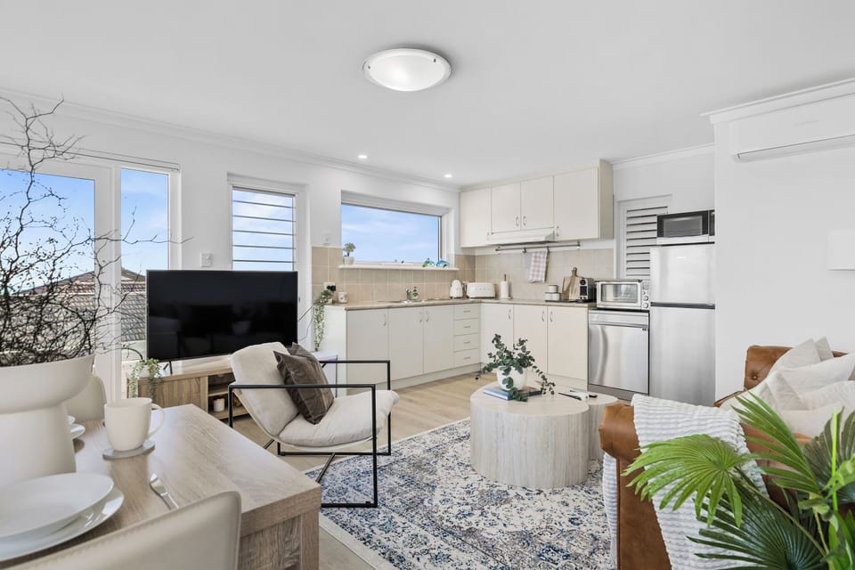 This cozy area, with a leather sofa and a modern armchair, is perfect for relaxing and watching TV. It flows into a well-equipped kitchen.