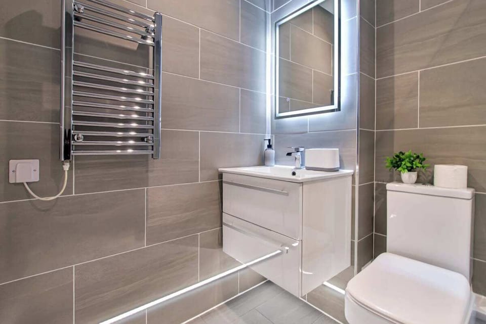 Modern Bathroom: A stylish and contemporary bathroom featuring a walk-in shower, sleek vanity unit, and illuminated mirror — designed to provide a comfortable and refreshing start to your day.
