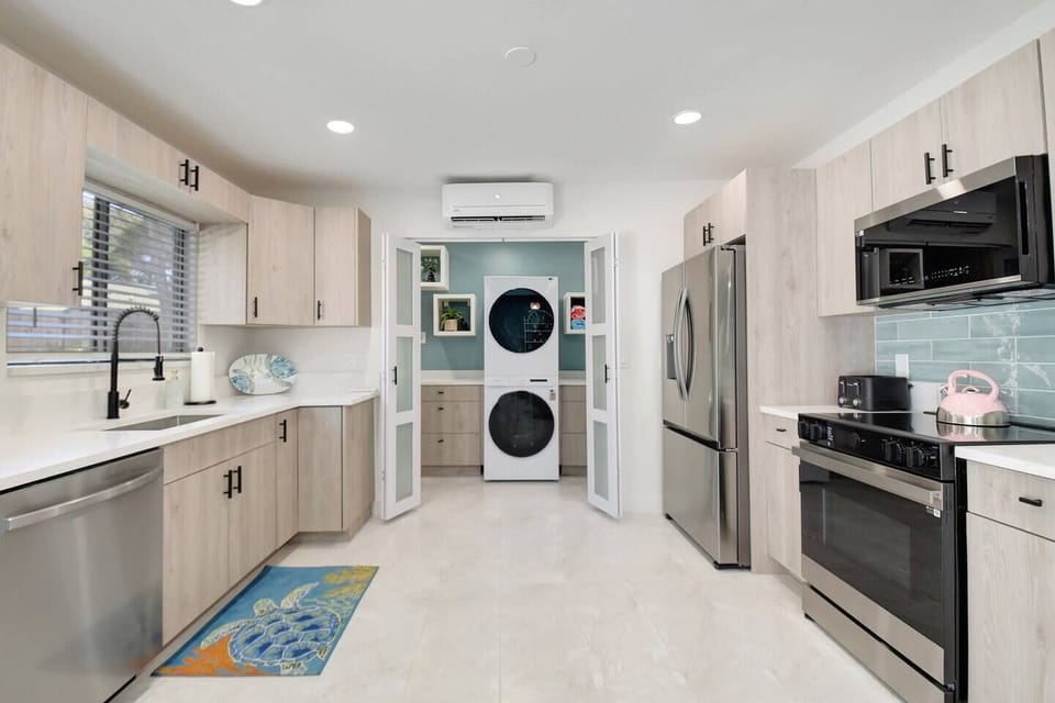 Bright kitchen with stainless steel fridge, sink view, and a cozy laundry nook for added convenience.