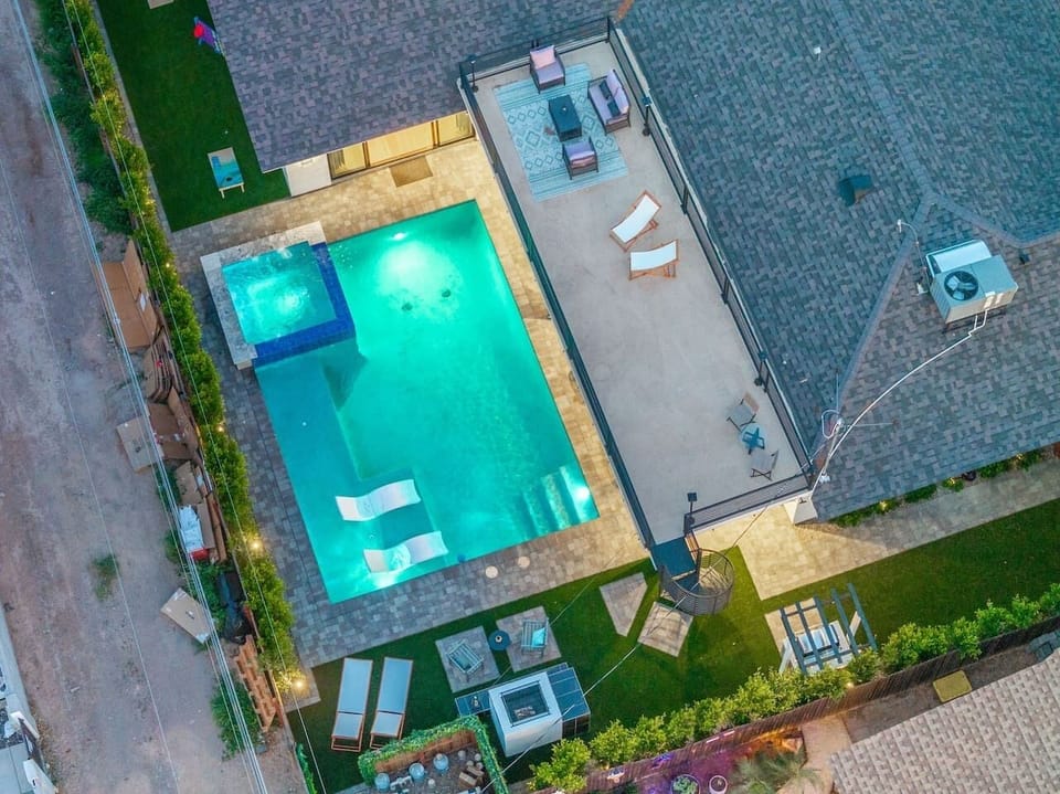 Bird’s-eye view of the ultimate outdoor haven: heated pool, rooftop lounge, and a custom fireplace seating area—all bathed in golden hour vibes.