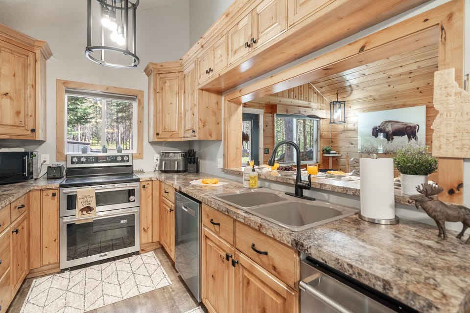 Cook with ease in a fully stocked kitchen featuring new appliances, warm rustic wood tones, and everything you need for meals at home during your Island Park stay