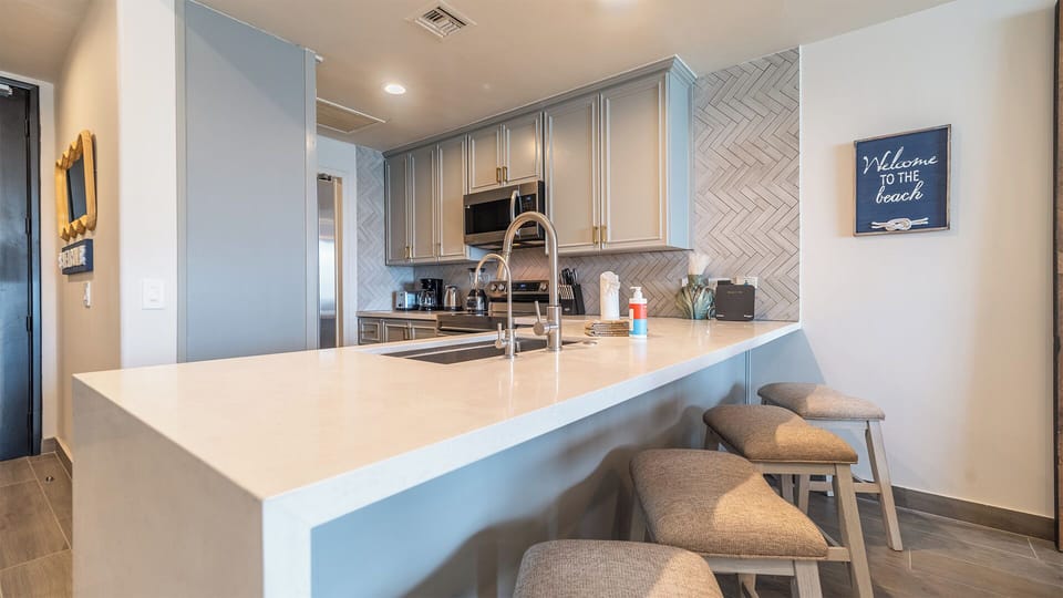 full kitchen with large counter top, all appliances, bar stools