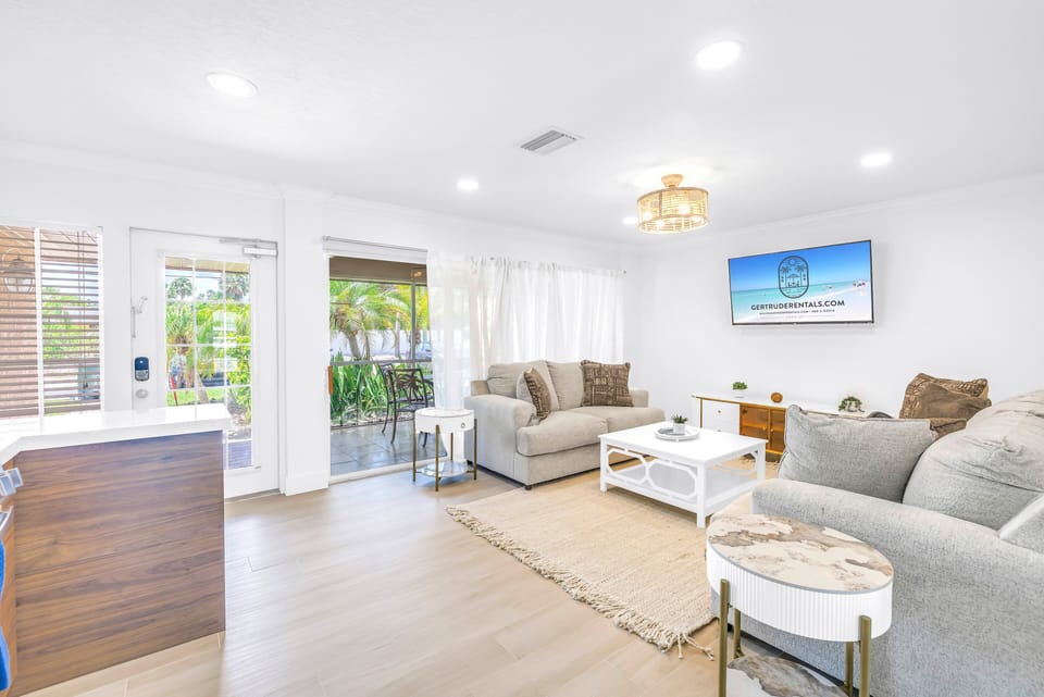 Open sunny living area leading to covered patio with tropical view.