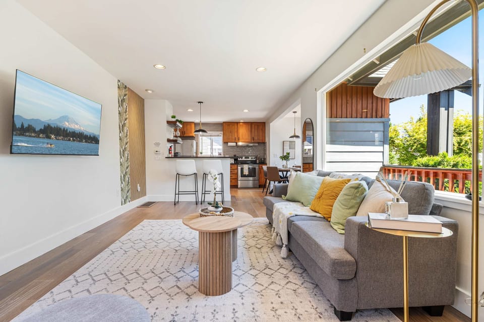 Open-concept living at its best—mustard-green pillows mirror the outdoor foliage, and the kitchen bar awaits your morning coffee ritual.