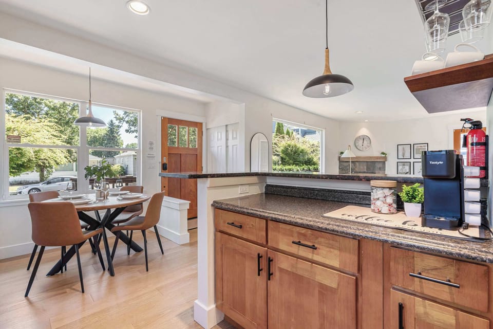 Morning coffee tastes better here - round wood table, comfy chairs, and garden views through expansive windows.