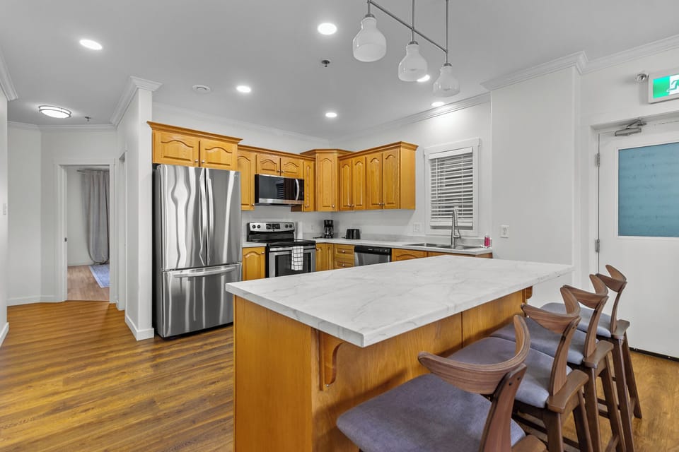 Charming kitchen with elegant wooden cabinets, stainless steel appliances, and a spacious marble island perfect for meal prep and gatherings.