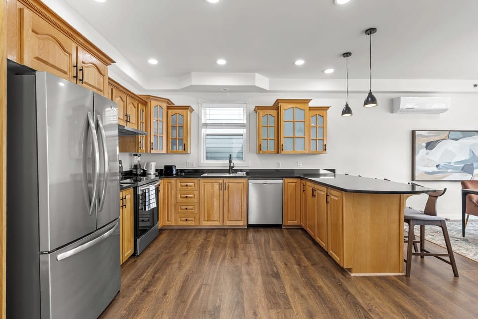 Spacious kitchen with modern appliances, warm wood cabinetry, and a sleek island—perfect for cooking and gathering!