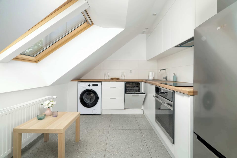 A wide-angle view of the kitchen area with the skylight overhead. The fridge stands near a small dining table, keeping everything within easy reach.