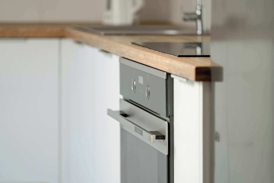 A closer perspective of the kitchen corner, showing the built-in oven and white cabinetry. The design blends functionality with simplicity.