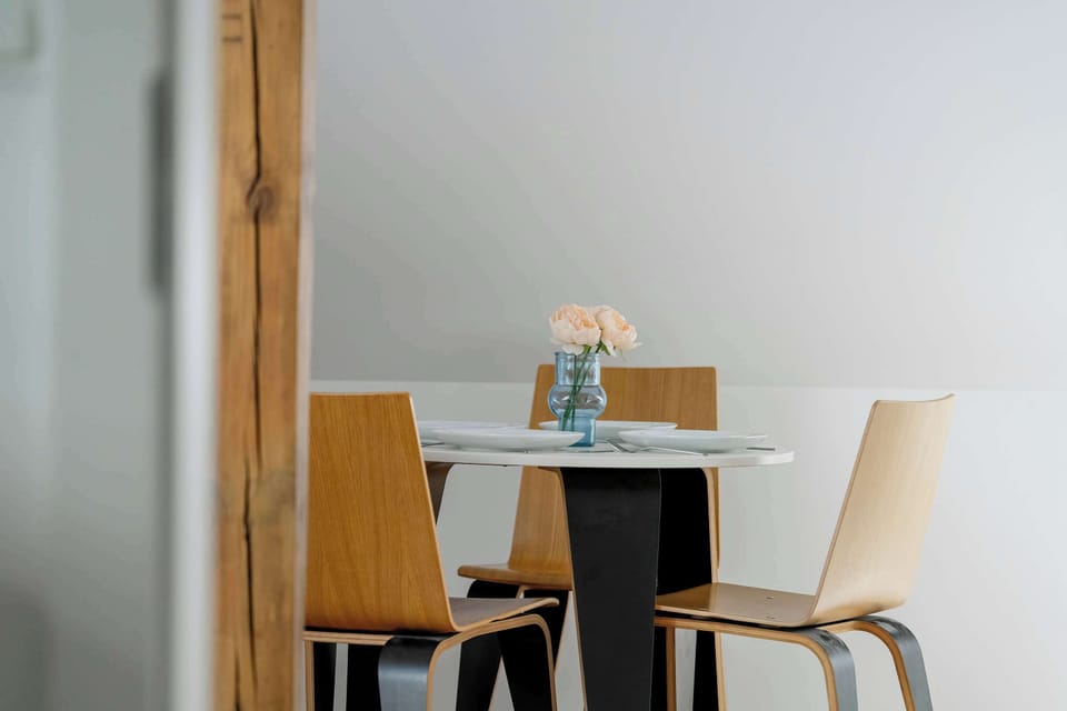 A decorative detail of a small table with a vase of pink flowers. The minimal setup brightens the otherwise neutral room.