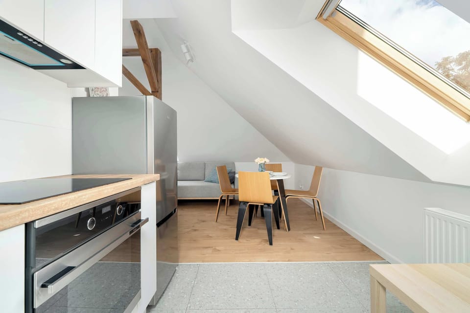 Another view of the kitchen, showing the fridge, stove, and skylight. The counter extends along the sloped wall, maximizing available space.