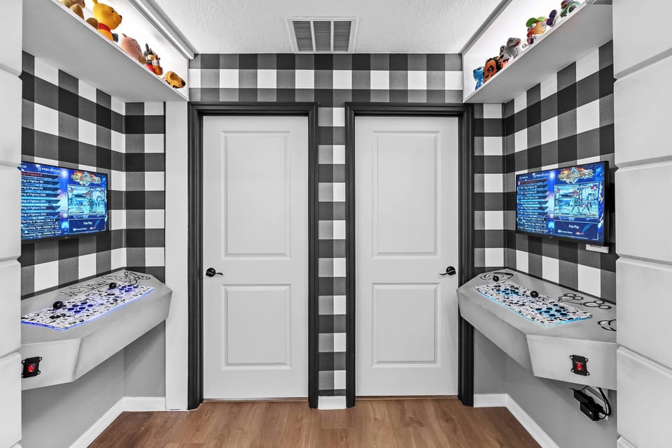 Step into a playful nook adorned with bold black-and-white checkered walls that add a unique flair. Two sleek game consoles await your next adventure, framed by cheerful decor that invites fun and relaxation for all ages.