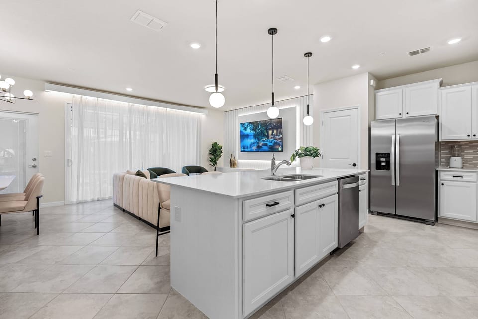 Welcome to this bright kitchen with sleek white cabinetry and a spacious island, ideal for meal prep or casual dining. Natural light floods in through large windows, creating a warm atmosphere for relaxation and conversation.