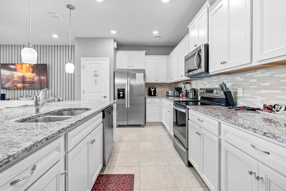 Welcome to this inviting kitchen with sleek white cabinetry, beautiful granite countertops, and modern stainless steel appliances. The pendant lighting adds warmth, making it perfect for your culinary adventures.