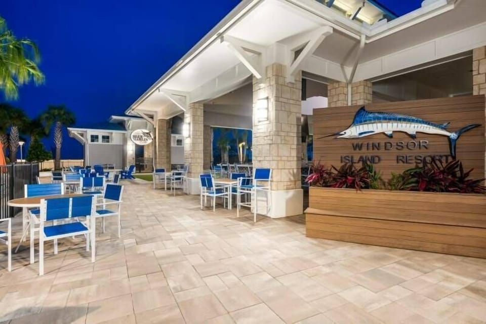 Step into a vibrant outdoor dining area where sleek blue chairs perfectly complement the warm stone accents. The inviting lighting creates a welcoming ambiance, ideal for enjoying a meal under the stars.
