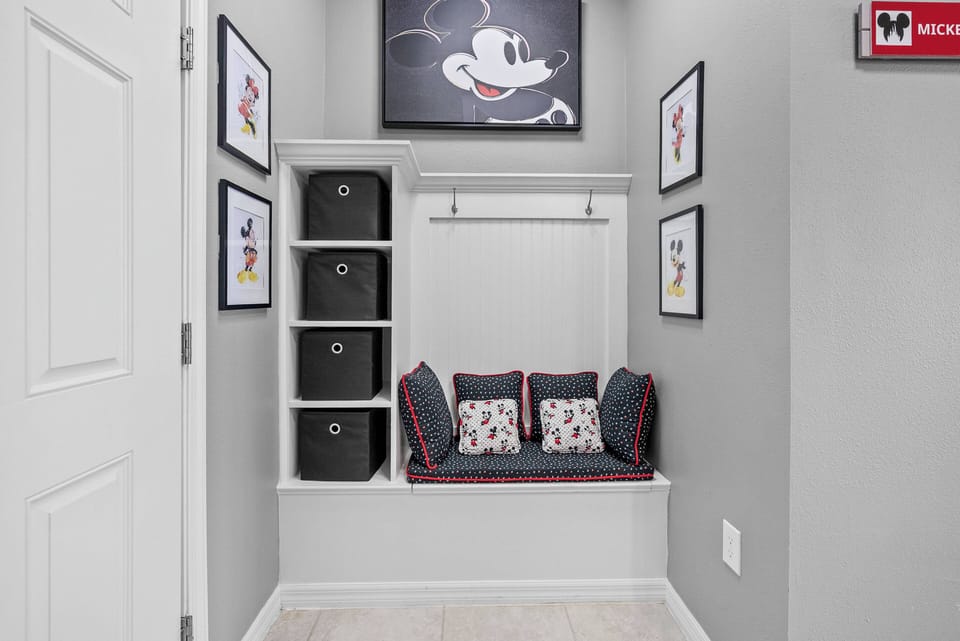 Discover a charming space that blends style and comfort, featuring a cozy built-in bench with fun cushions. The soft gray walls provide a calm backdrop for whimsical Mickey Mouse art, while organized shelving keeps your.