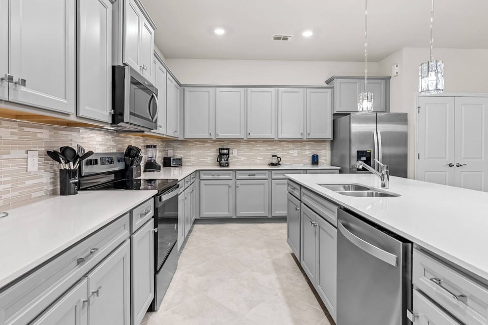 This stylish kitchen boasts sleek gray cabinetry and elegant quartz countertops, offering ample space for meal prep. With modern appliances and chic pendant lighting, it sets the perfect atmosphere for your culinary adventures.