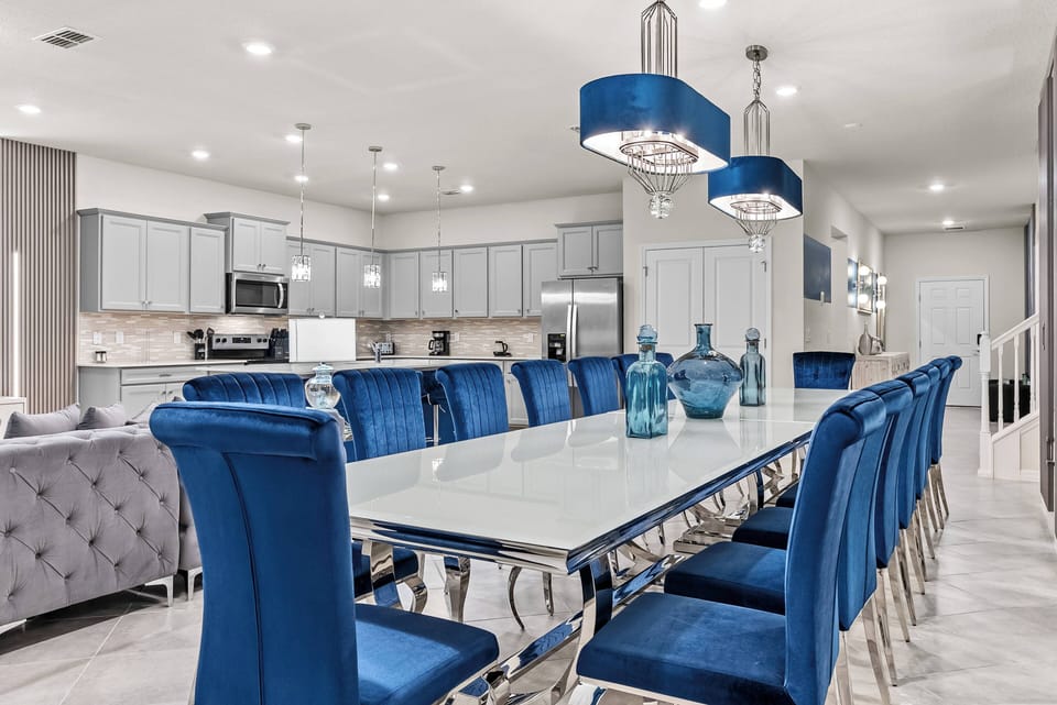 Enjoy a vibrant dining area with a sleek glass table and plush blue chairs, ideal for gatherings. The modern cabinetry and stylish light fixtures set a welcoming atmosphere for shared meals and laughter.