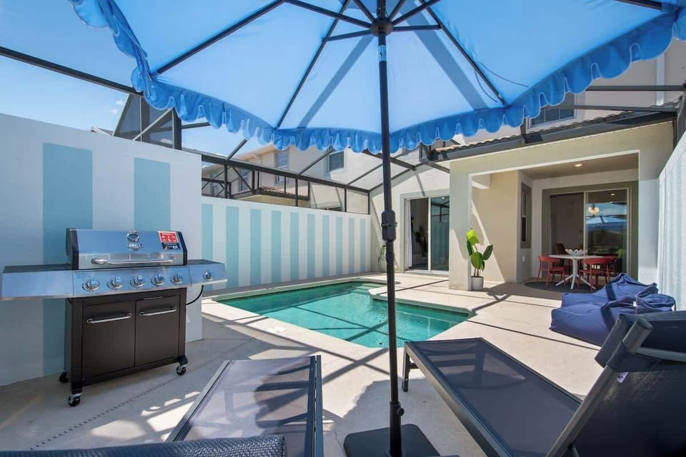 Private screened-in pool area featuring lounge chairs, a BBQ grill, and vibrant greenery. Perfect for relaxing under the sun or enjoying a family BBQ in a serene and secure setting