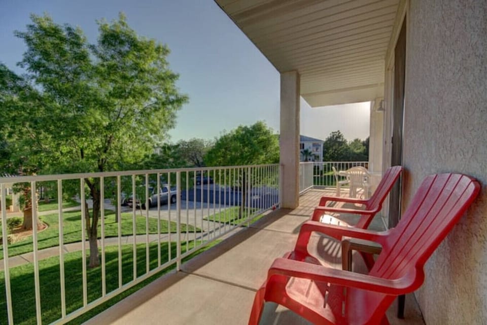 Huge Balcony overlooking the trees and grass with pools nearby.