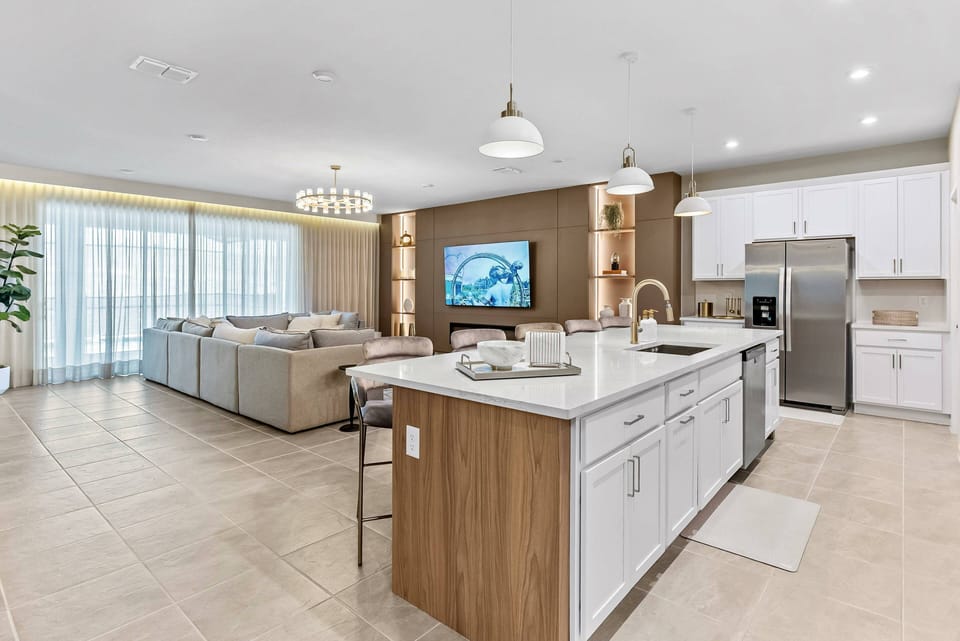 Experience a bright, airy kitchen with sleek white cabinetry and warm wood accents. The spacious island is perfect for casual dining, and large windows flood the space with natural light, making it ideal for gatherings.