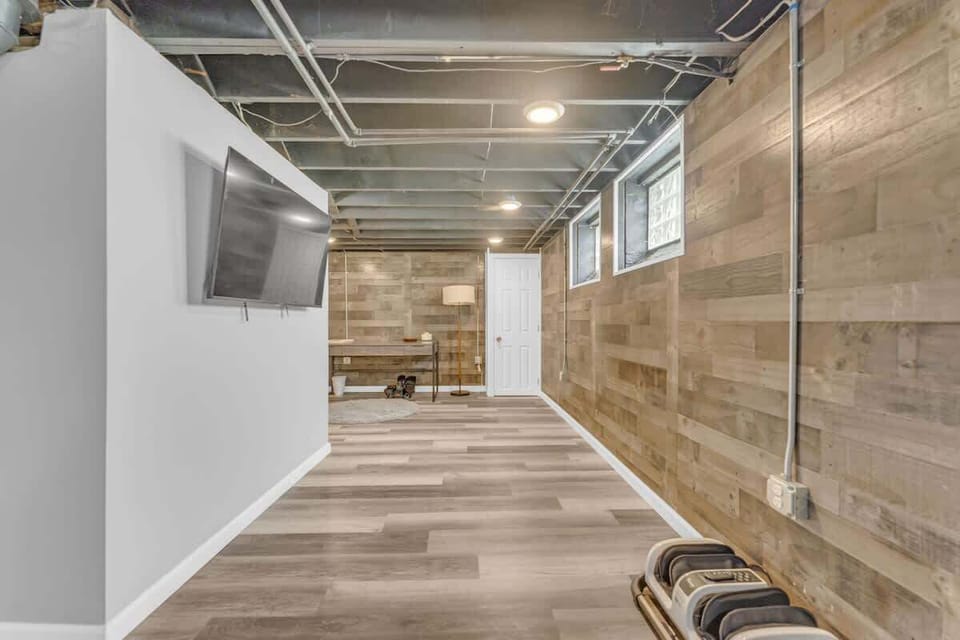 Spacious basement area w/ wall-mounted TV, wood accent wall & open layout
