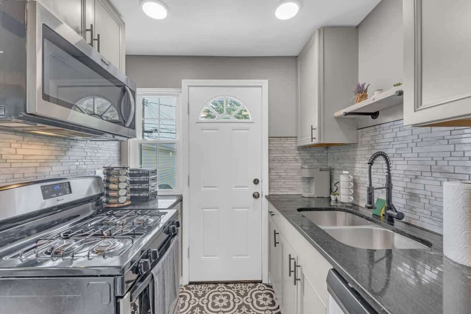 Bright galley kitchen w/ stainless appliances, tile backsplash & ample counter space