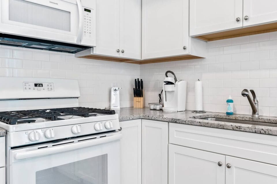 A bright, modern kitchen corner with sleek white cabinets, a cozy coffee station, and a clean gas stove ready for cooking ☕✨
