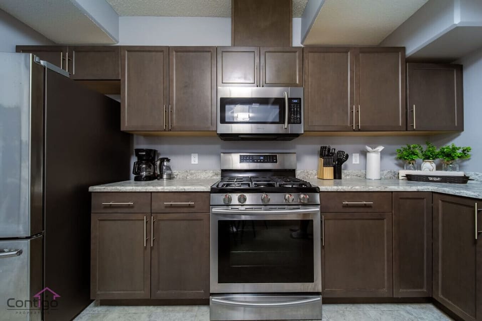 Fully equipped modern kitchen with stainless steel appliances, microwave, and coffee maker, perfect for preparing home-cooked meals during your stay.