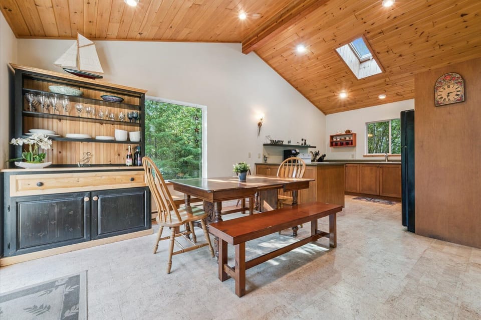 Fully equipped kitchen with vaulted ceilings and skylight, designed to make every meal feel special. Gather around the dining table, enjoy locally curated treats from your welcome package, and take in the peaceful forest setting.