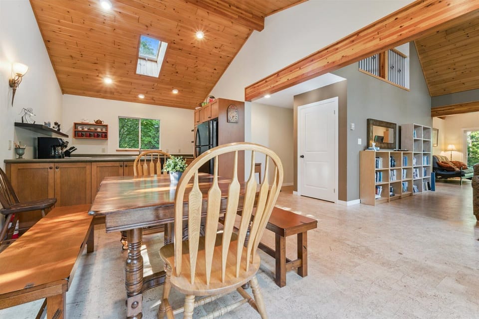 Spacious open-concept dining area with vaulted pine ceilings and skylight, seamlessly connected to the kitchen and living space — ideal for family gatherings after a day exploring Tobermory.