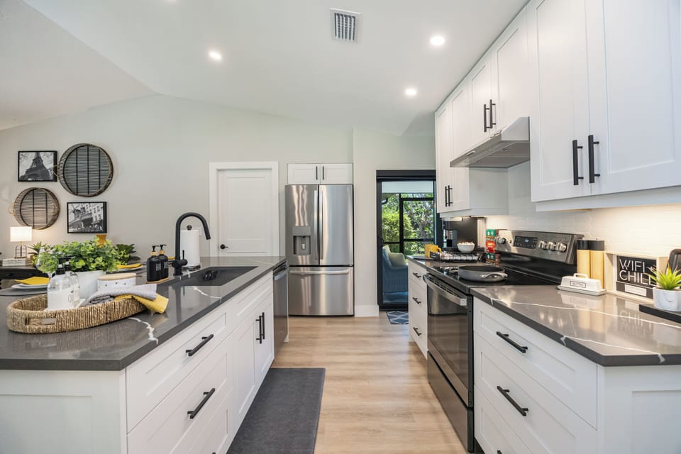 Bright renovated kitchen - white shaker, quartz, stainless; slider to lanai.