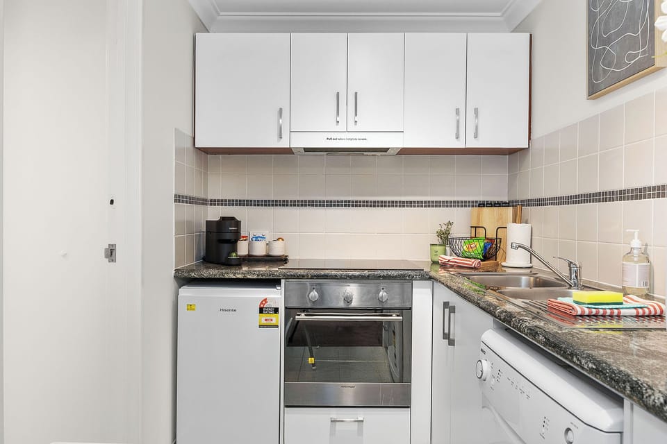 Bright, functional kitchen with granite countertops, stove, oven, and coffee machine, plus a front-load washing machine for laundry