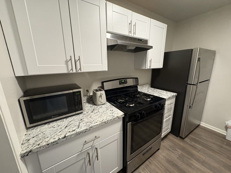 Modern and practical kitchen equipped with refrigerator, gas stove, microwave and toaster