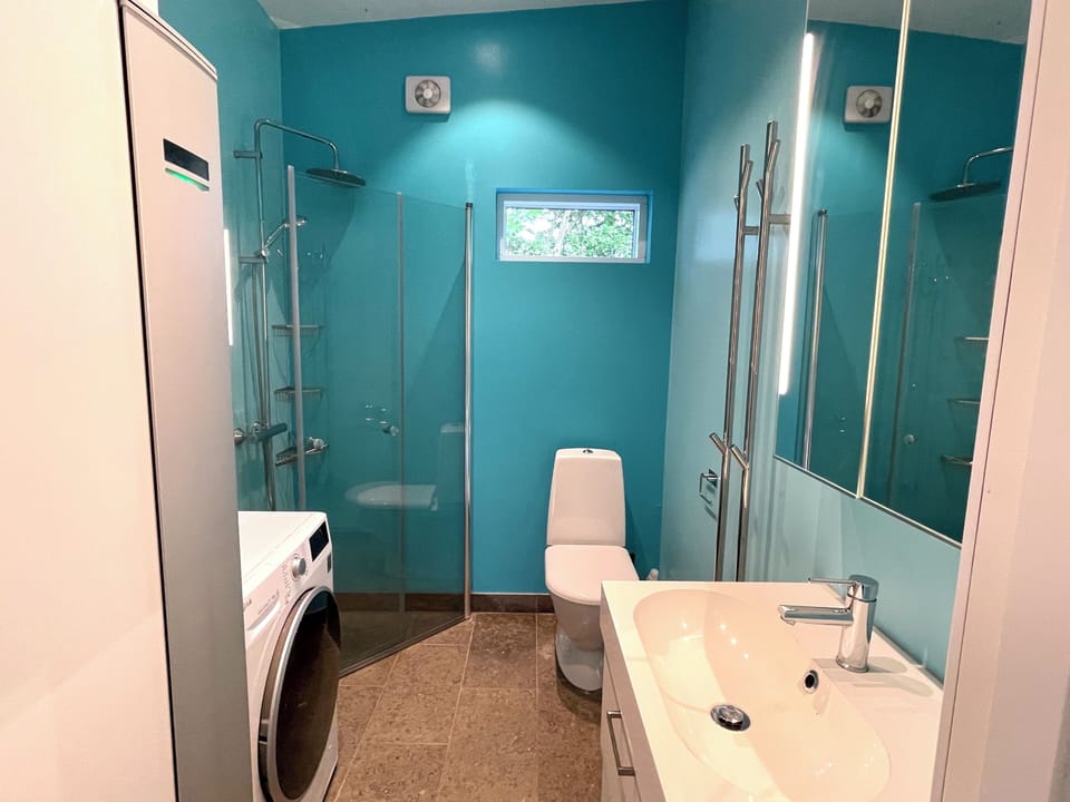 Bathroom with shower, washer/dryer, and limestone floor.