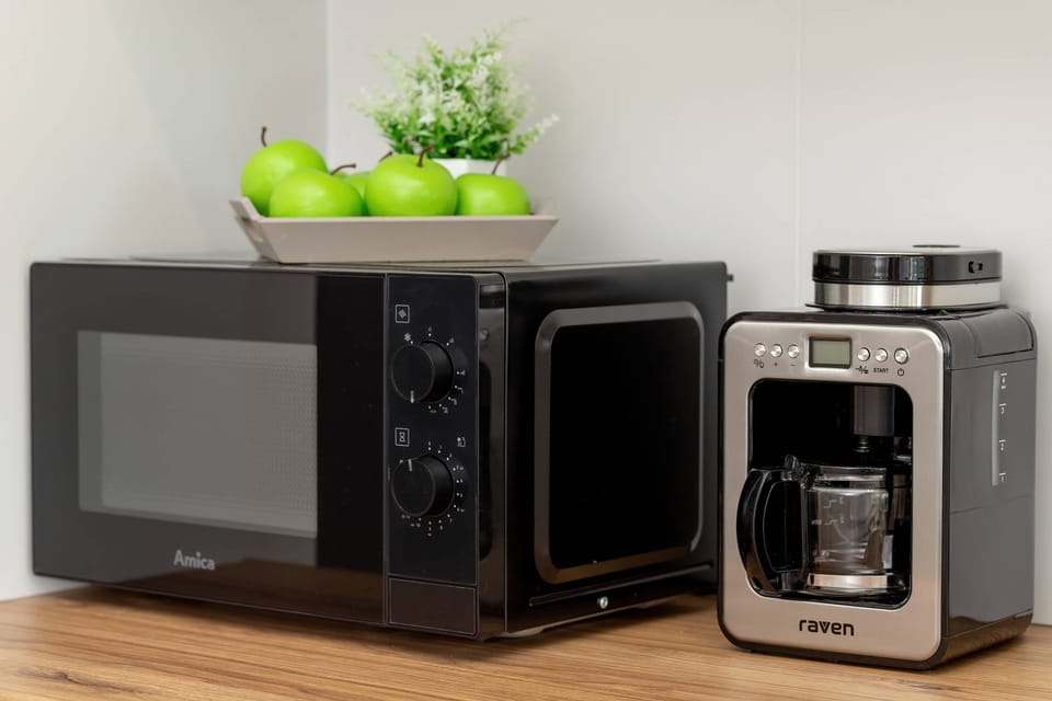 Small kitchen counter with a microwave, coffee machine, and a fruit bowl.