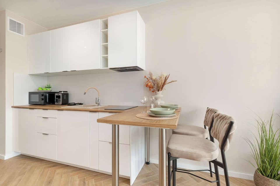 Compact open-plan kitchen with modern cabinets, a small dining table, and neutral décor.