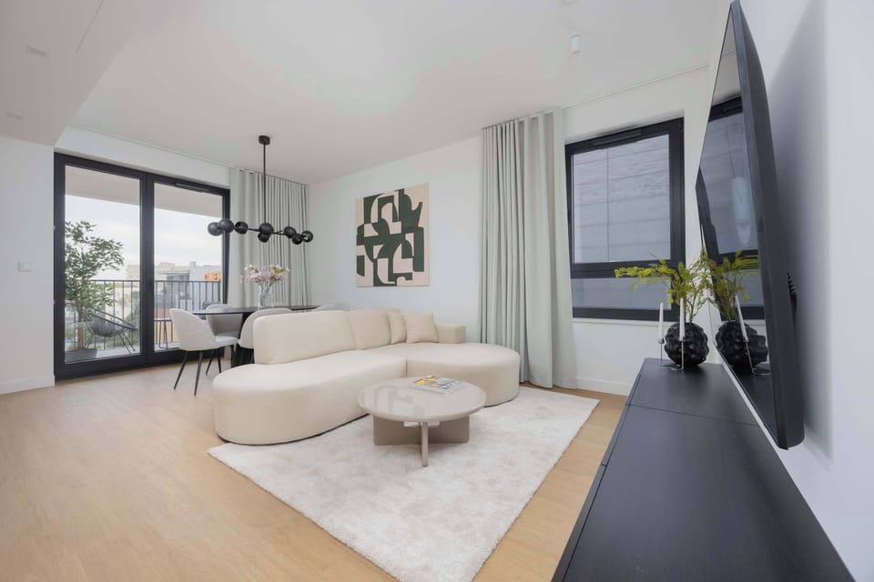 A bright corner of the living room with a round coffee table, large windows.