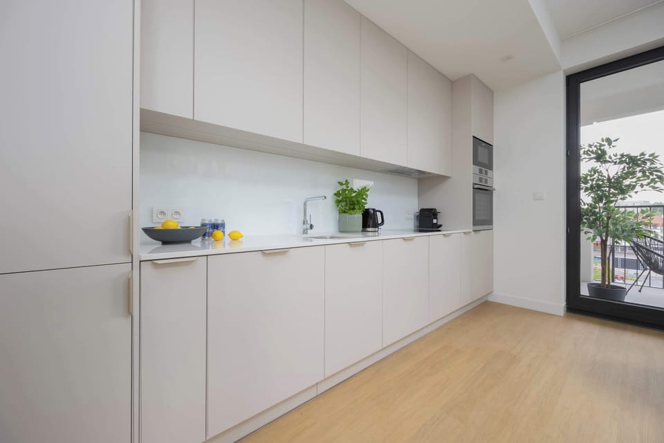 A modern kitchen with white cabinets, a built-in oven, and a clean, minimalist design.