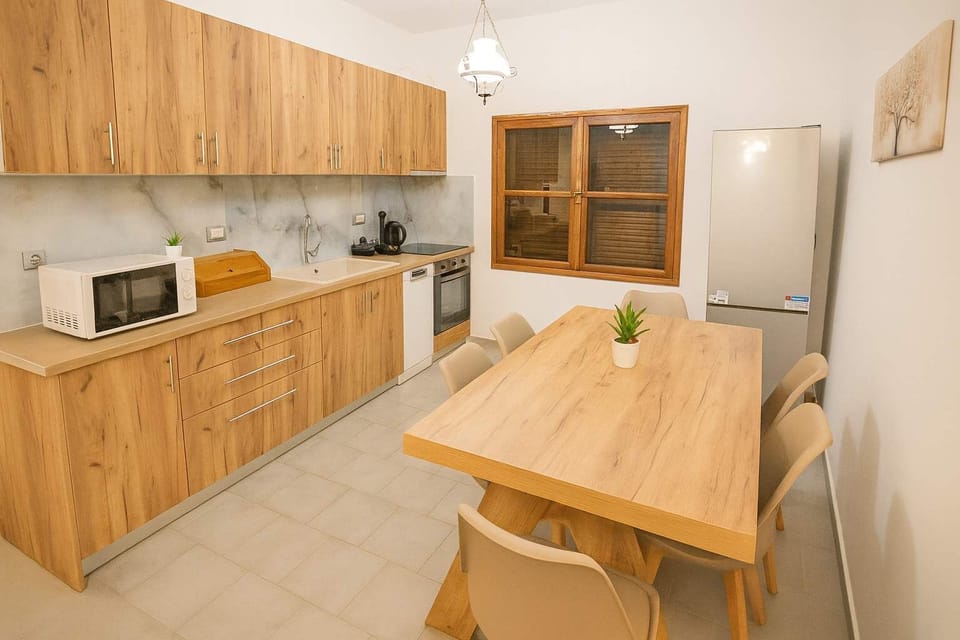 Warm and Functional Kitchenette with Dining Table – Thoughtfully designed cooking space featuring modern appliances, ample countertop space, and essential cookware, complemented by a sturdy wooden dining table, perfect for enjoying freshly meals