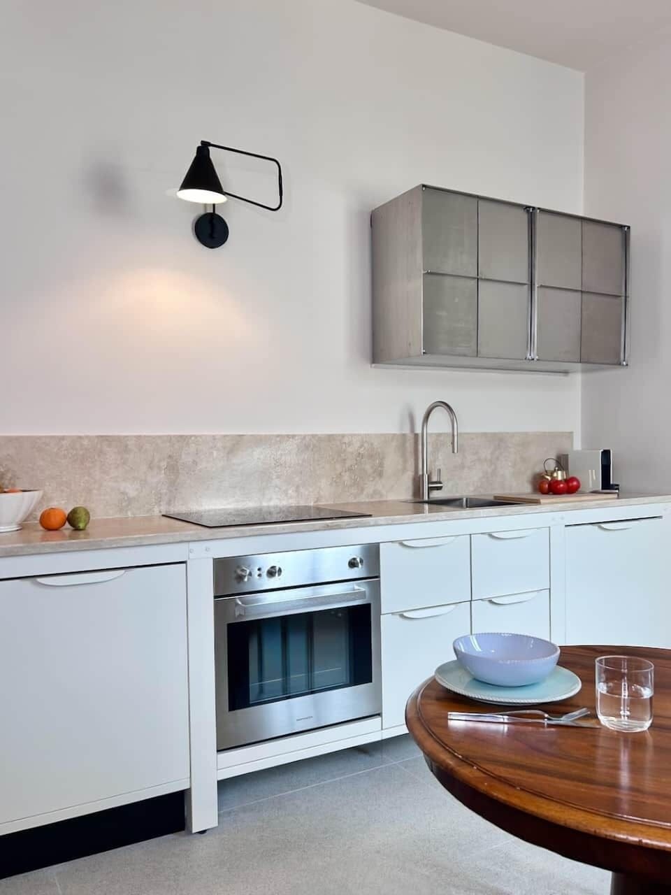 A stylish mid-century kitchen featuring metal, marble, full appliances, and everyday conveniences