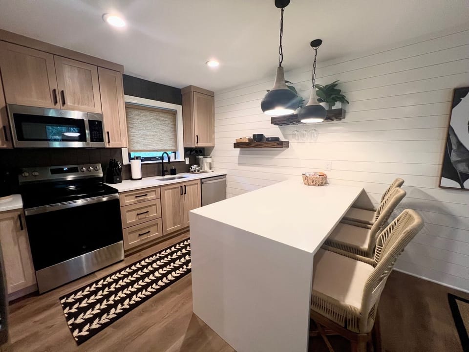 Whip up delicious meals in this modern kitchen featuring stainless steel appliances, a deep farmhouse sink, and stylish light wood cabinetry.