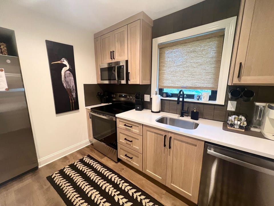 Gather around the sleek quartz breakfast bar for morning coffee. Features chic woven barstools and easy access to the well-stocked coffee station.