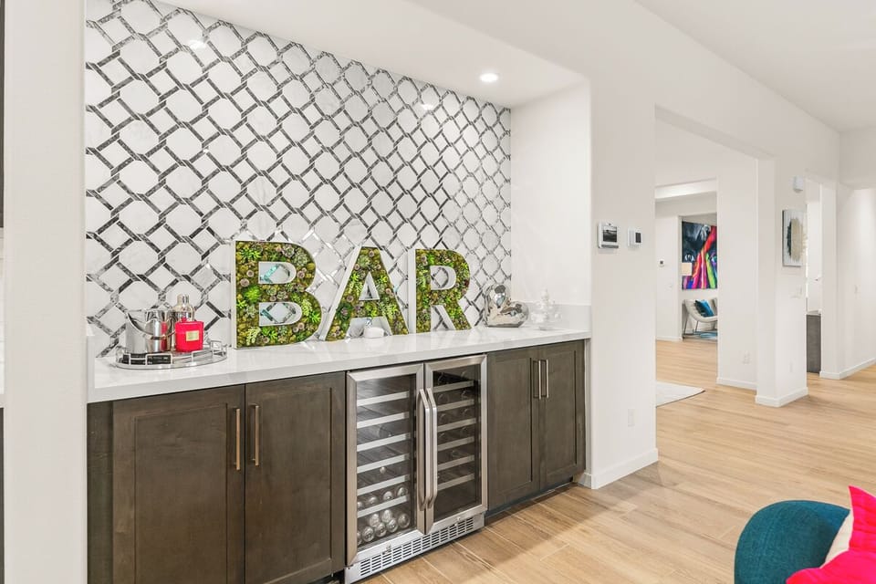 Wet bar with dual beverage fridges and trendy moss "BAR" sign.