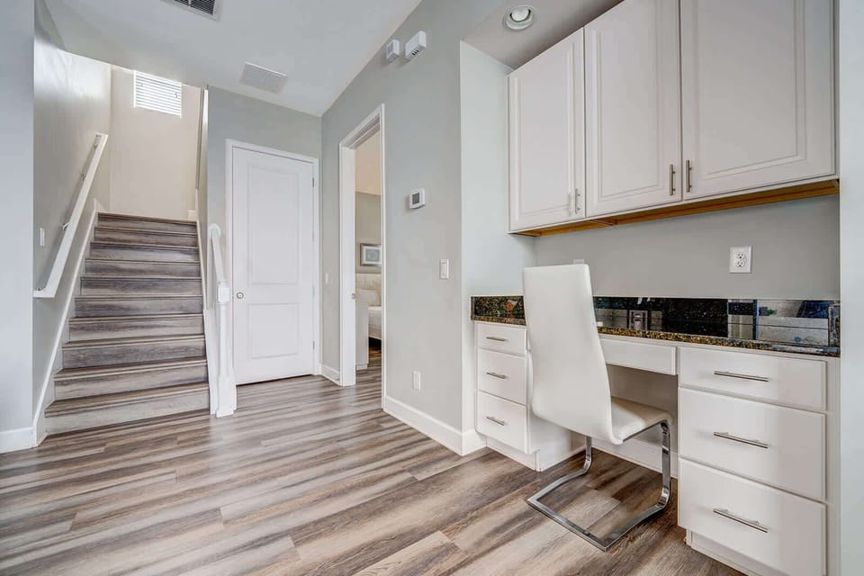 Modern workspace with built-in desk and storage next to a staircase.