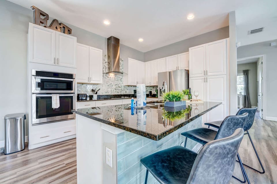 Modern kitchen with a large granite island and seating for three.