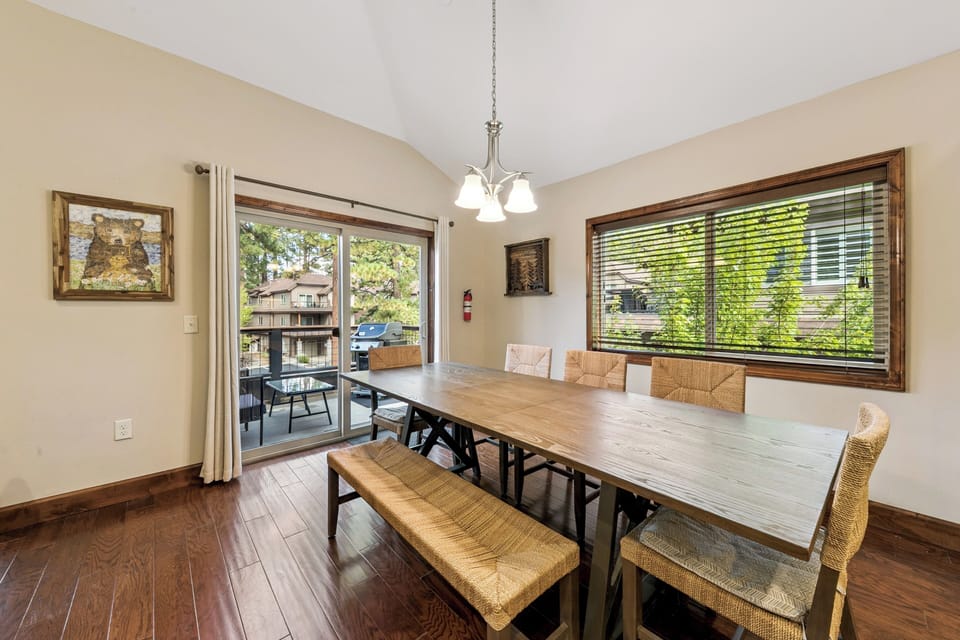 Gather around this spacious dining table where memorable meals unfold, with natural light streaming through large windows and balcony access.