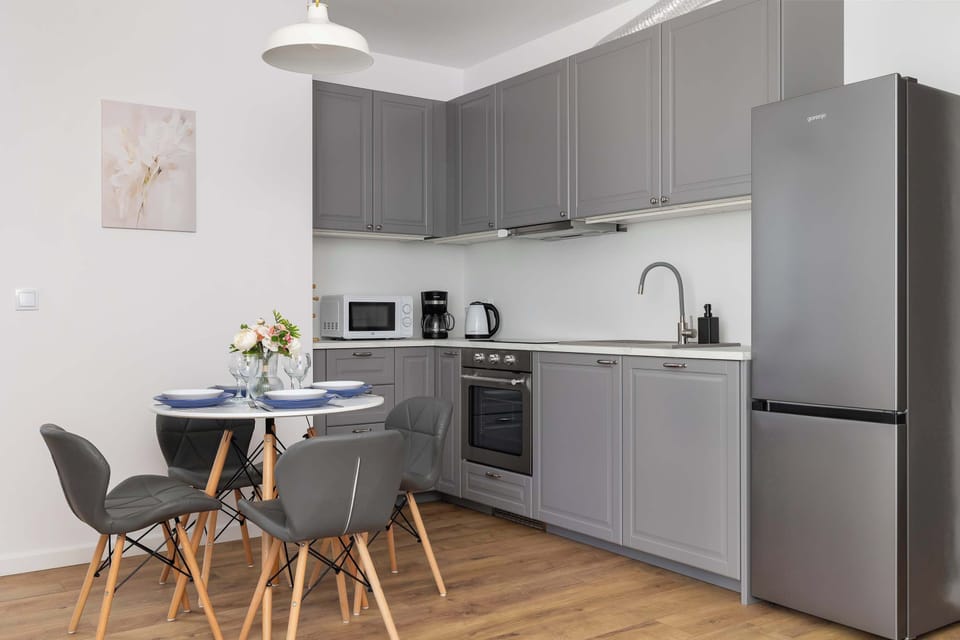A contemporary kitchen with integrated appliances and a small dining space. Ideal for preparing and enjoying home-cooked meals.