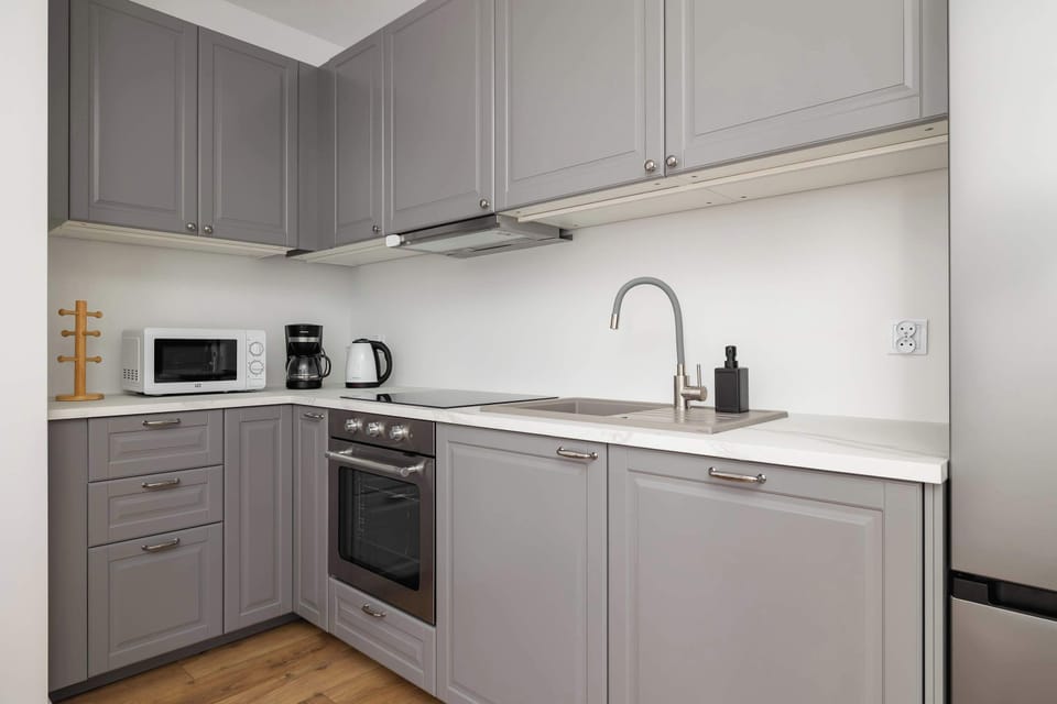 A sleek kitchen with gray cabinets, white countertops, and built-in appliances. Designed for functionality and style.