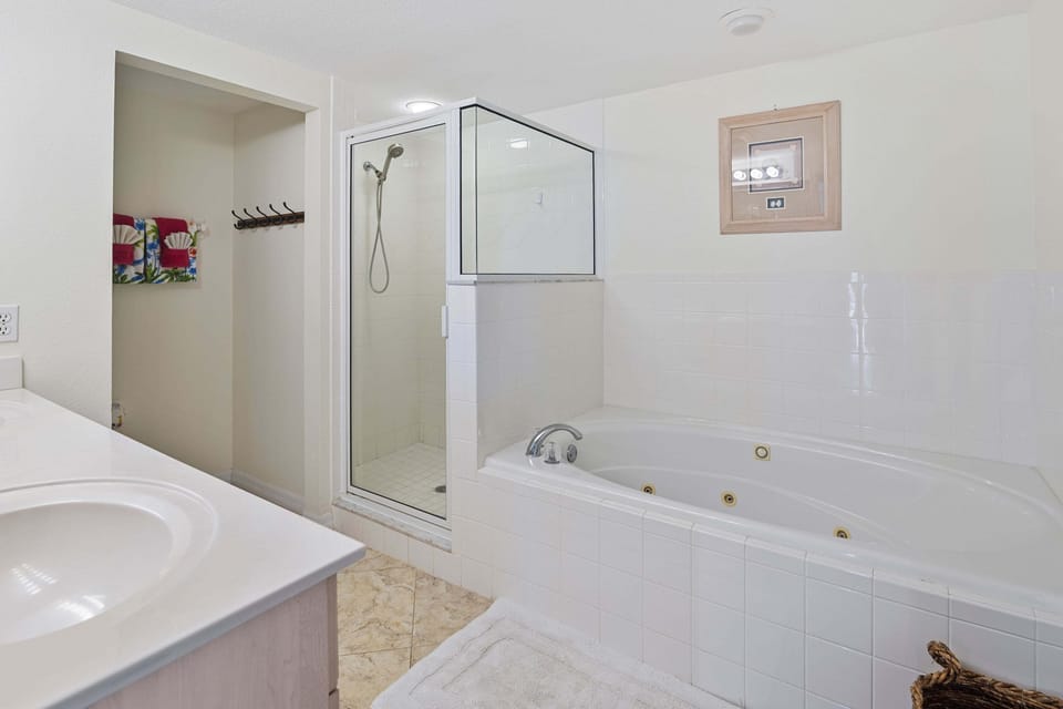 Unwind after a day at the beach in this spa-like bathroom featuring a jetted soaking tub, walk-in shower, and dual vanity sinks—perfect for relaxation during your coastal getaway.